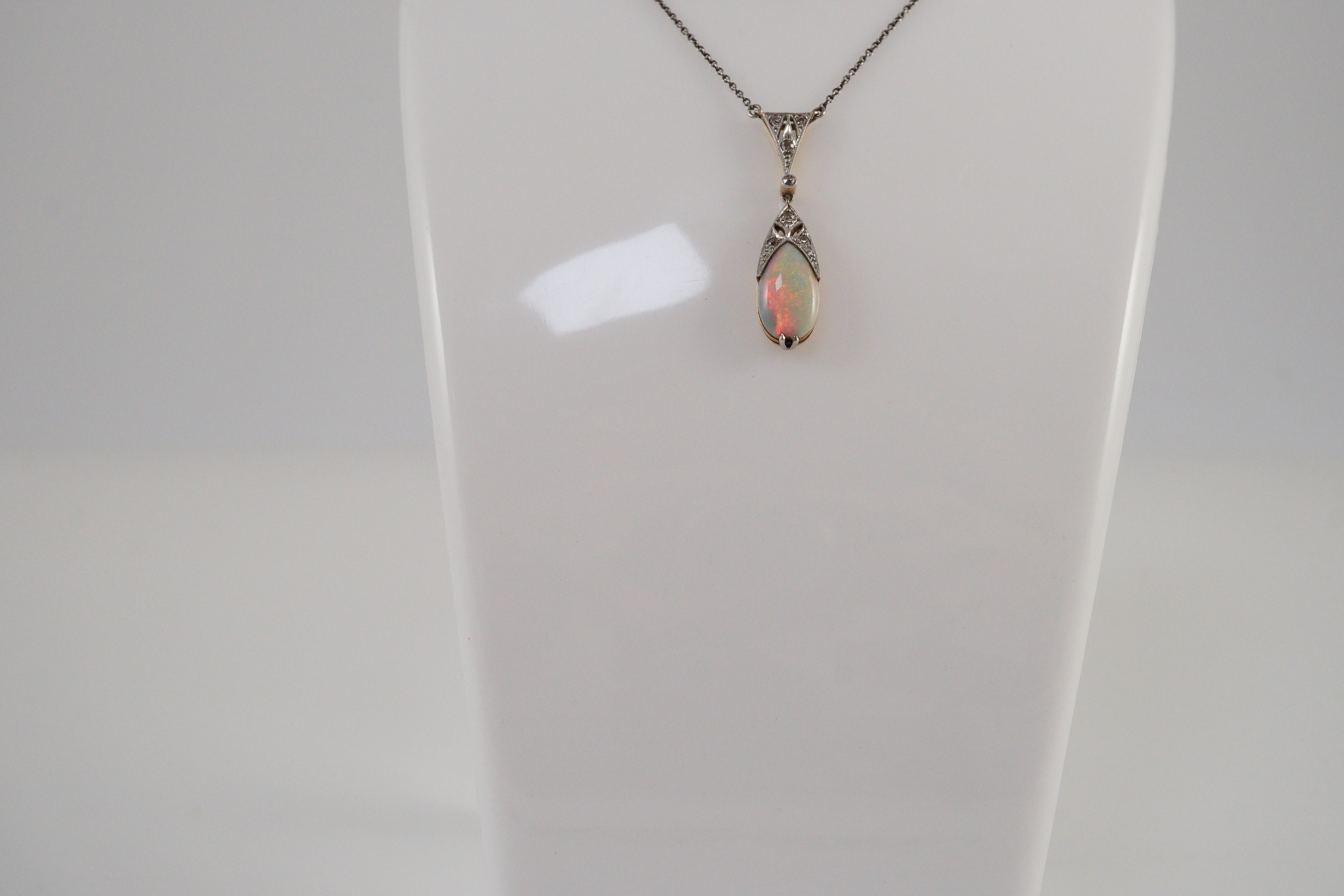 A 1920's gold and platinum, white opal and millegrain set diamond cluster pear shaped drop pendant necklace
